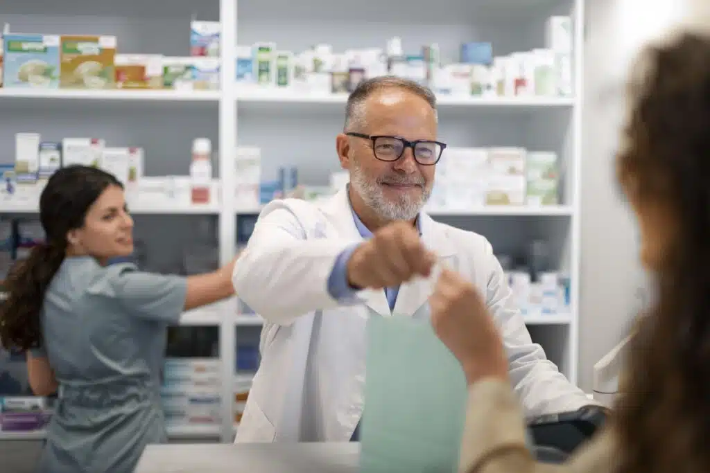 Photo of a pharmacist handing something to a customer. Mortgages for pharmacists.