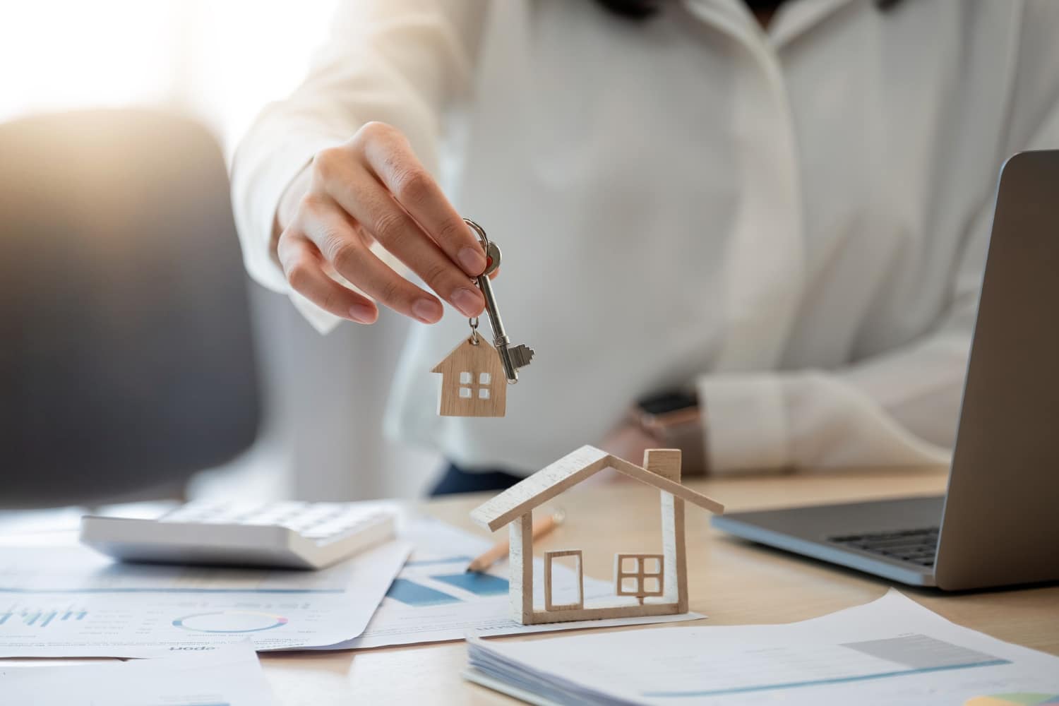 Female hand holding house key,real estate agent woman working house loan at