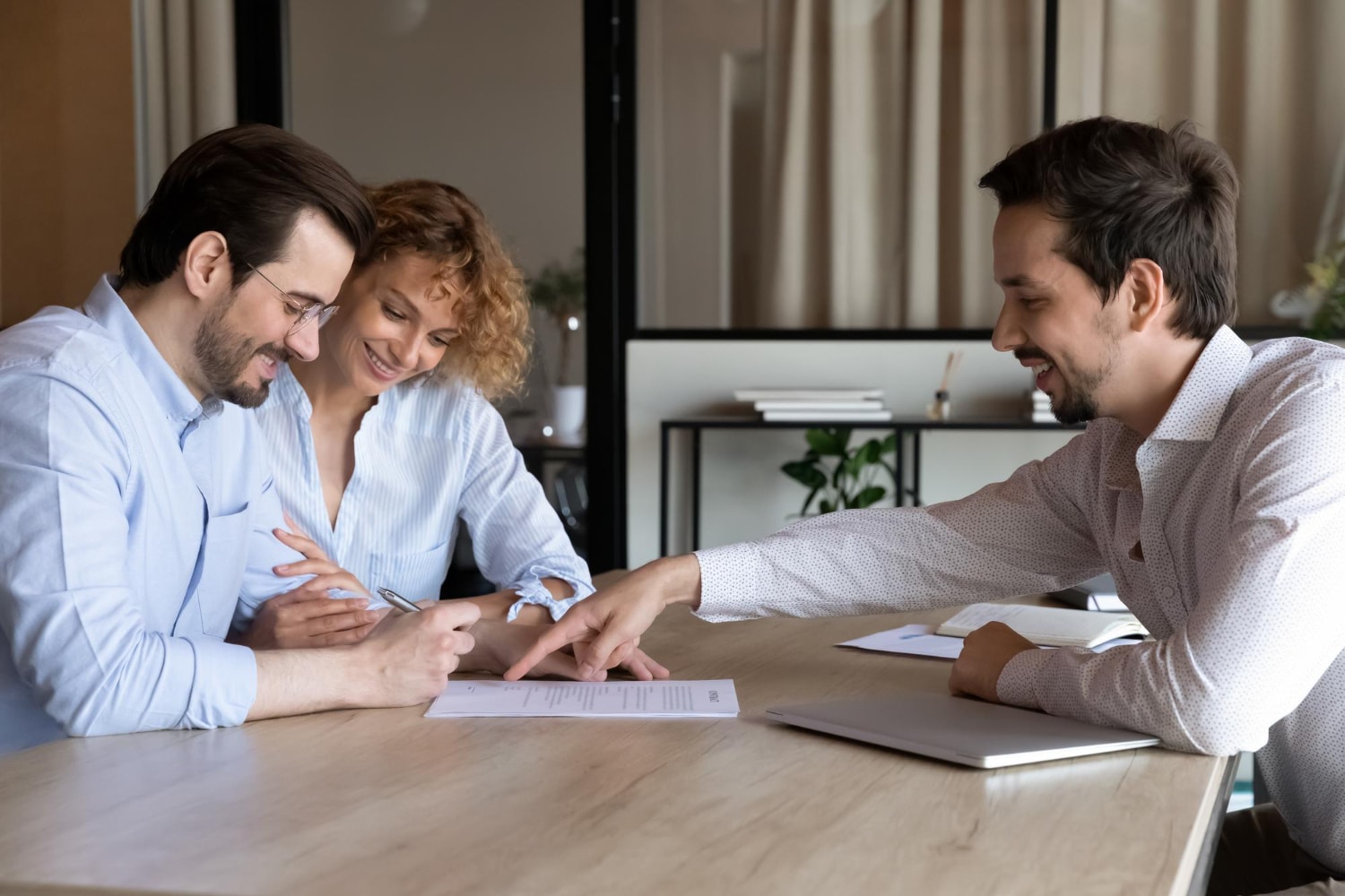 Happy couple of clients signing contract with agent